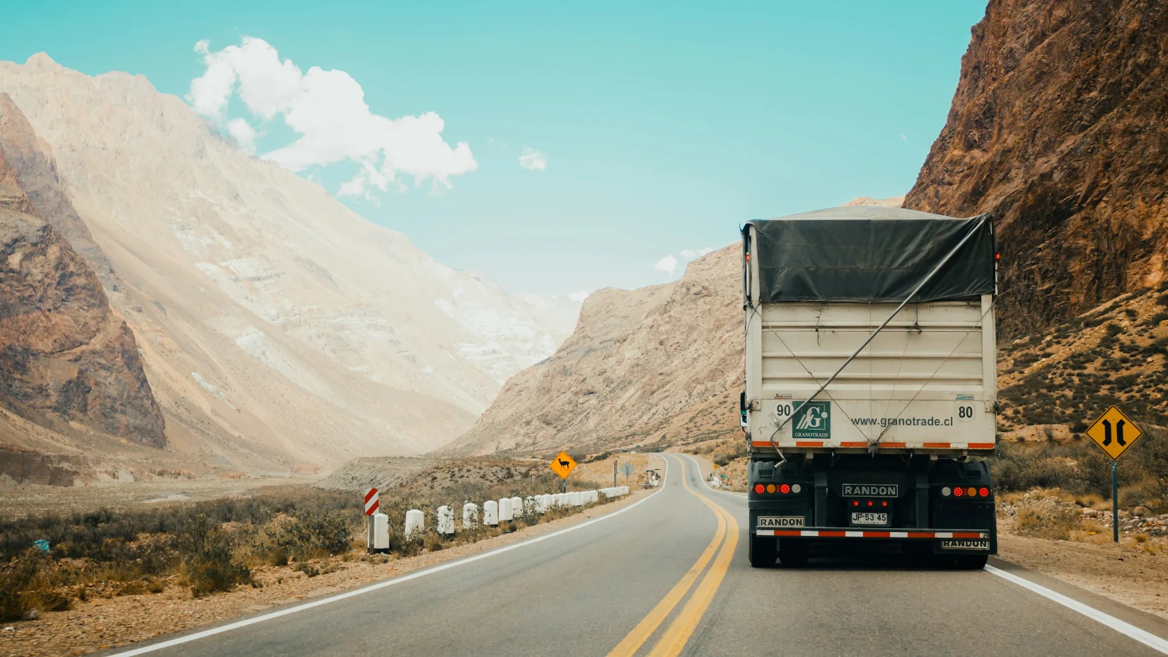 White semi-truck driving on a mountain highway at dusk